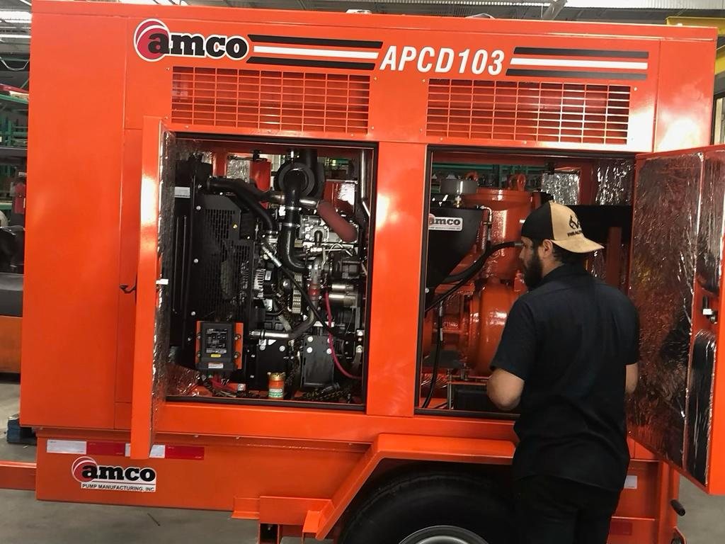 AMCO technician servicing the diesel engine inside an APCD103 sound-attenuated auto-prime unit