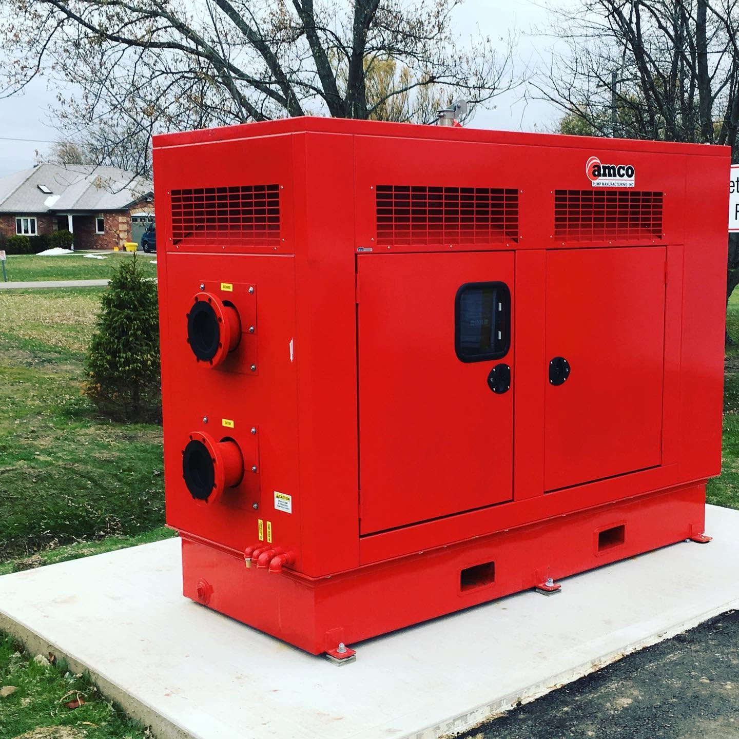 Red AMCO sound-attenuated pump enclosure installed on a concrete pad in Lincoln, Ontario, Canada